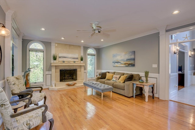 living area featuring a wainscoted wall, recessed lighting, ornamental molding, light wood-style floors, and a tile fireplace