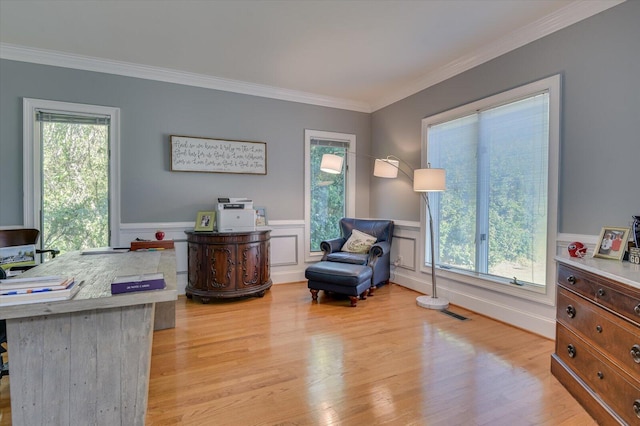 home office with light wood-type flooring, a wainscoted wall, and a healthy amount of sunlight