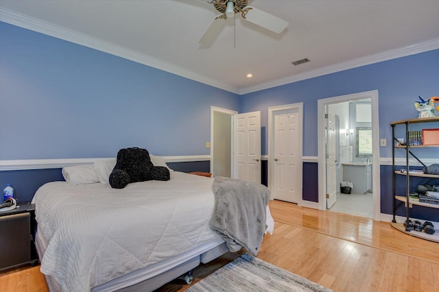 bedroom featuring light wood-type flooring, ensuite bath, ceiling fan, and crown molding