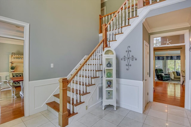 stairway featuring a decorative wall, wainscoting, tile patterned floors, and crown molding