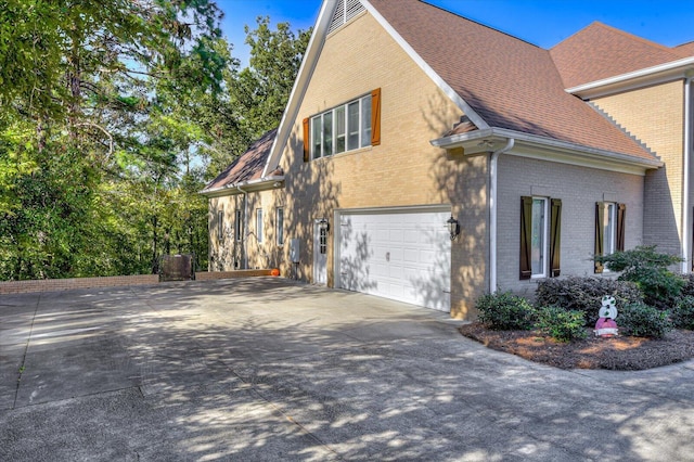 view of property exterior with concrete driveway, brick siding, roof with shingles, and an attached garage