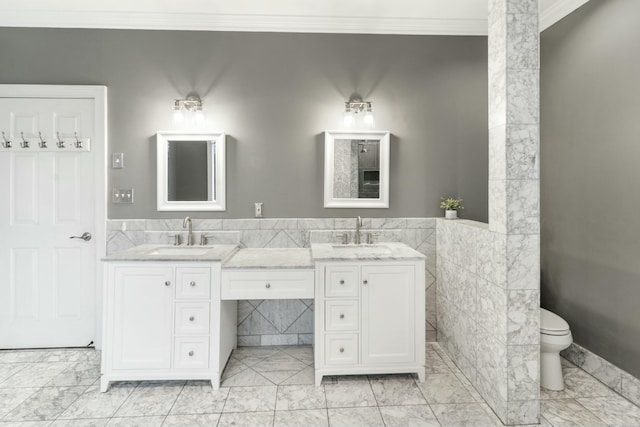 bathroom with crown molding, marble finish floor, a sink, and double vanity