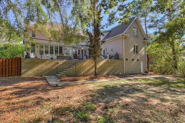 back of house with brick siding, stairway, and fence