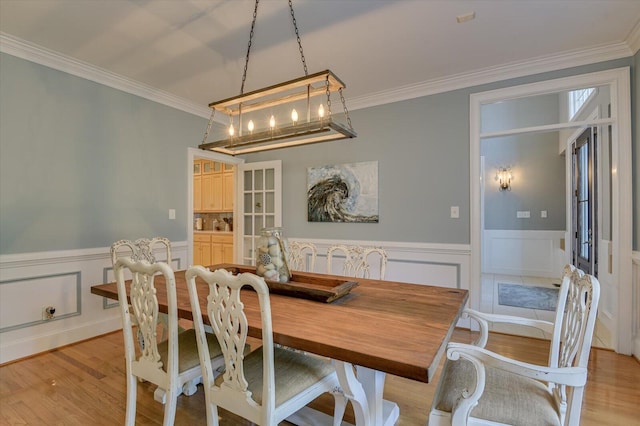 dining area with a wainscoted wall, light wood-type flooring, and crown molding