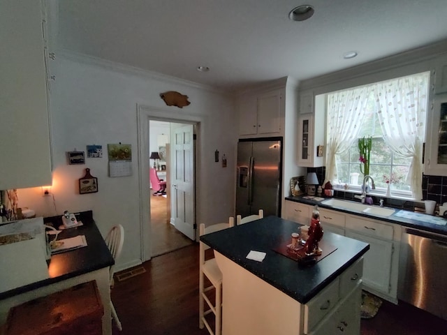 206 S Alexander Ave, Washington, GA 30673 - kitchen featuring crown molding, white cabinets, a sink, appliances with stainless steel finishes, and a kitchen island