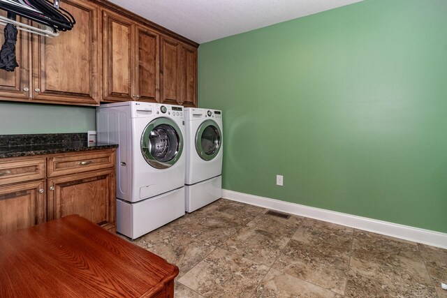 laundry room with washer and clothes dryer, cabinets, and a textured ceiling