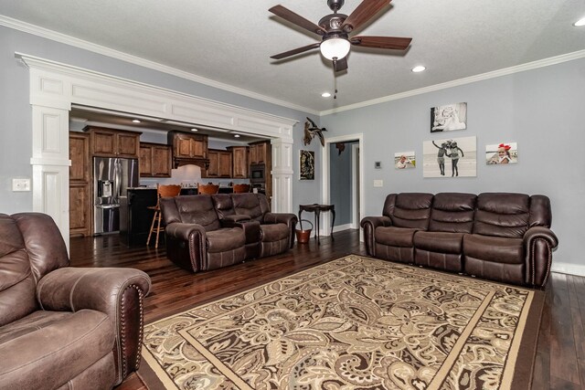 living room featuring dark wood-type flooring, ornate columns, ceiling fan, and crown molding