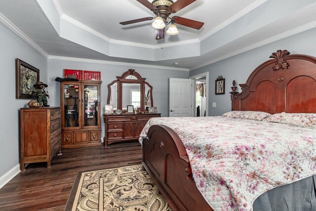 bedroom featuring a tray ceiling, ceiling fan, ornamental molding, and dark hardwood / wood-style floors