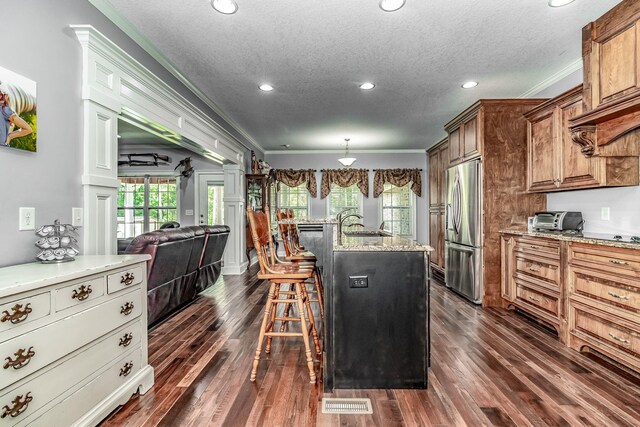 kitchen featuring a kitchen island with sink, crown molding, and stainless steel refrigerator with ice dispenser