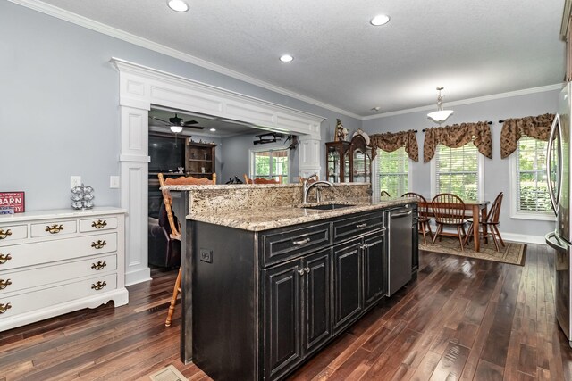 kitchen featuring a breakfast bar, sink, dishwasher, white cabinetry, and an island with sink