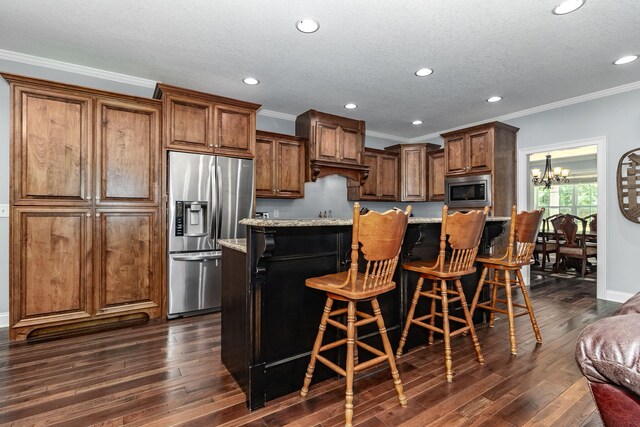 kitchen with a breakfast bar, a center island, light stone countertops, and appliances with stainless steel finishes