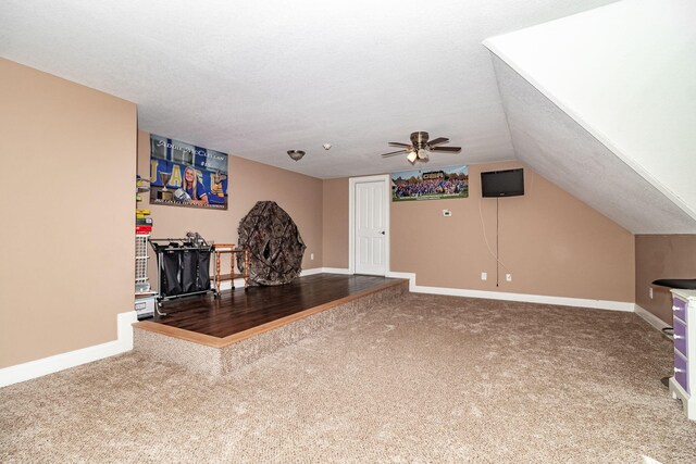 unfurnished living room with vaulted ceiling, ceiling fan, carpet, and a textured ceiling