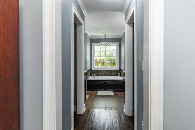 hall featuring dark hardwood / wood-style flooring, ornamental molding, and an inviting chandelier