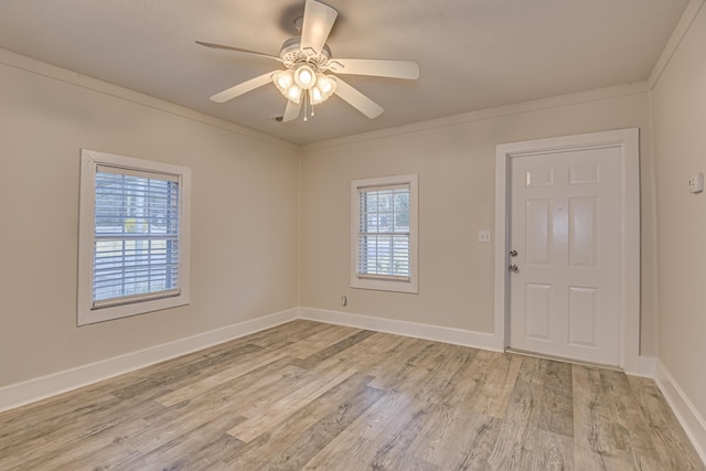 empty room with crown molding, light wood-style flooring, plenty of natural light, and baseboards