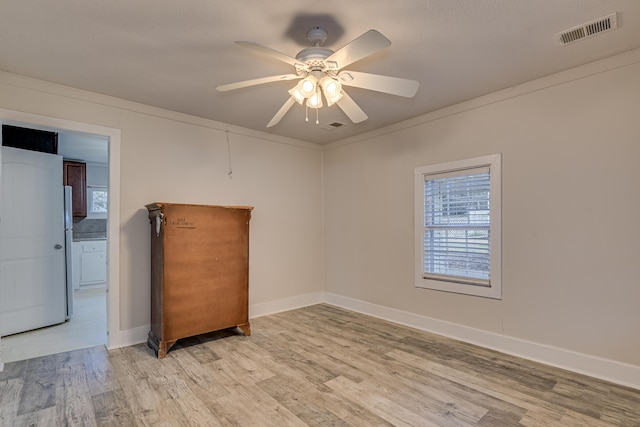 unfurnished room featuring baseboards, light wood-style floors, visible vents, and ceiling fan