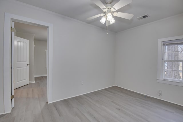 spare room with light wood-style floors, visible vents, and ornamental molding