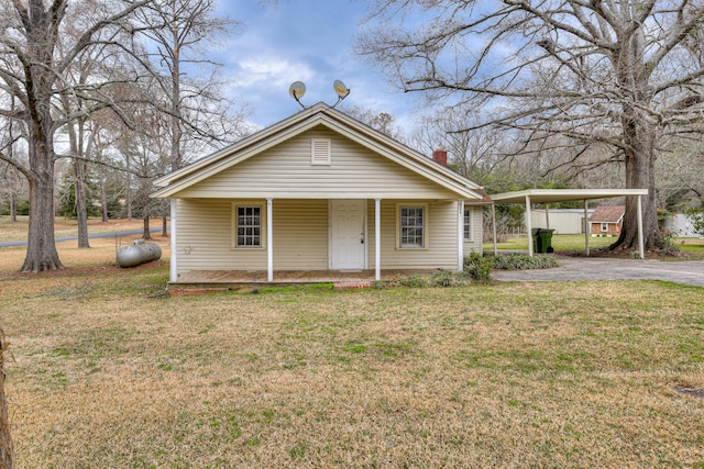 bungalow featuring a front yard, a porch, a chimney, a carport, and aphalt driveway