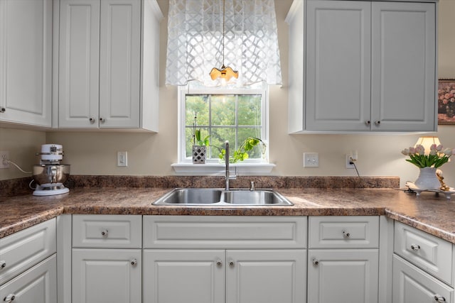 kitchen featuring a sink, white cabinetry, and dark countertops