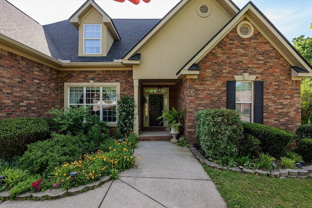doorway to property with brick siding and roof with shingles