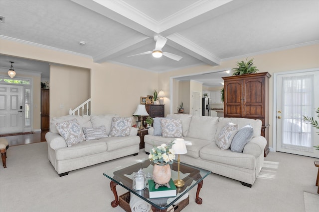 living area featuring beamed ceiling, ornamental molding, light colored carpet, and a ceiling fan