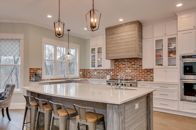 649 Bent Creek Dr, Evans, GA 30809 - kitchen with a kitchen island with sink, a sink, decorative backsplash, appliances with stainless steel finishes, and crown molding
