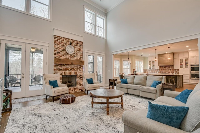 649 Bent Creek Dr, Evans, GA 30809 - living area featuring a brick fireplace, crown molding, light wood-style flooring, french doors, and a high ceiling
