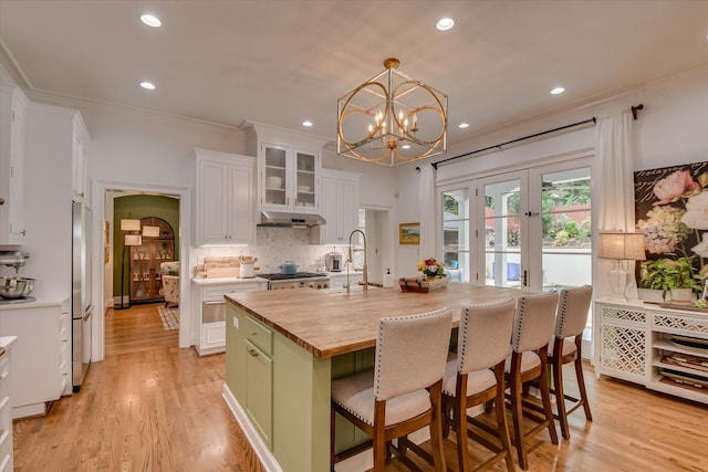 704 Summergate Ct, Augusta, GA 30909 - kitchen with butcher block countertops, freestanding refrigerator, under cabinet range hood, white cabinets, and backsplash