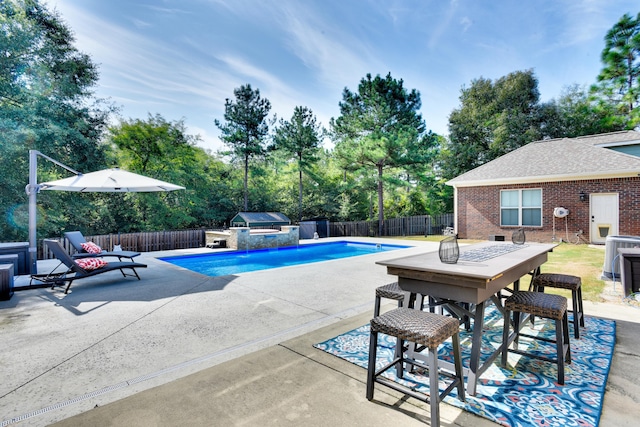 view of pool with pool water feature, an outdoor kitchen, a patio, and grilling area