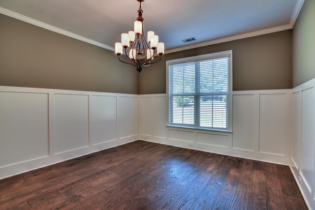 spare room featuring crown molding, dark wood-type flooring, and a notable chandelier