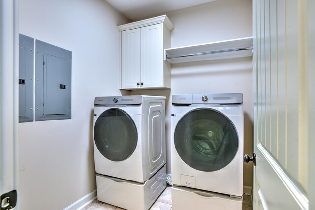 clothes washing area with washer and dryer, cabinets, and electric panel