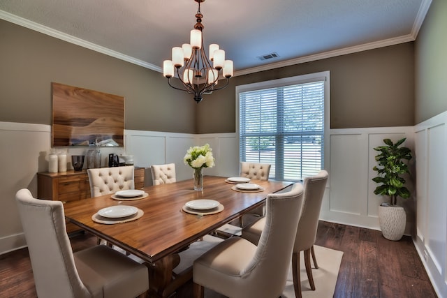 dining space with dark wood-type flooring, ornamental molding, and an inviting chandelier