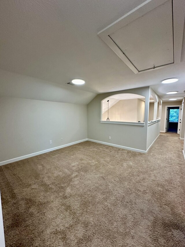 spare room featuring carpet flooring and vaulted ceiling