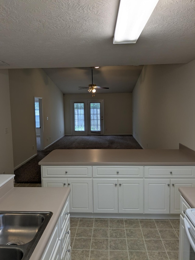 kitchen featuring a textured ceiling, ceiling fan, white cabinets, and vaulted ceiling