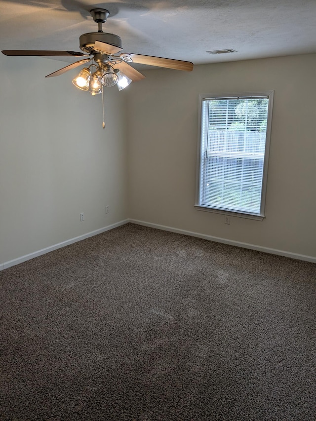 empty room featuring a ceiling fan, visible vents, carpet, and baseboards