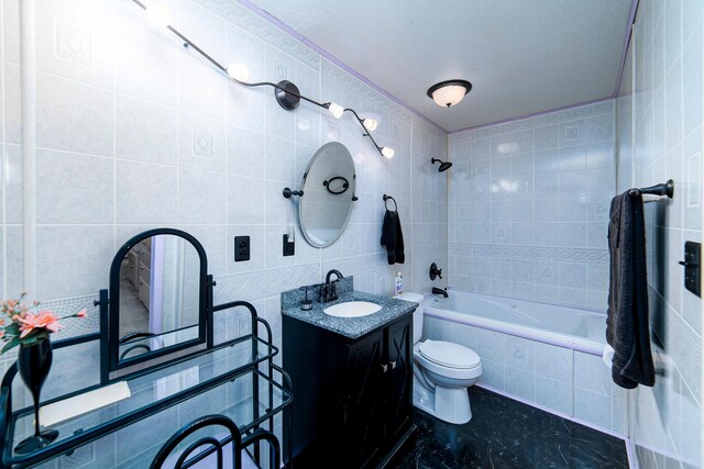 full bathroom featuring vanity, a textured ceiling, tile walls, toilet, and tiled shower / bath