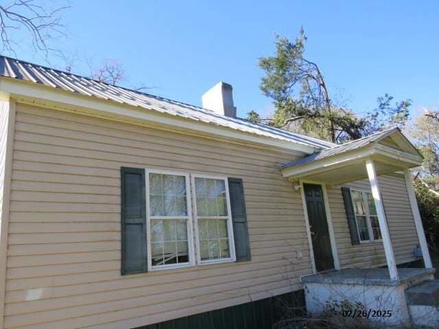 view of side of home with metal roof and a chimney