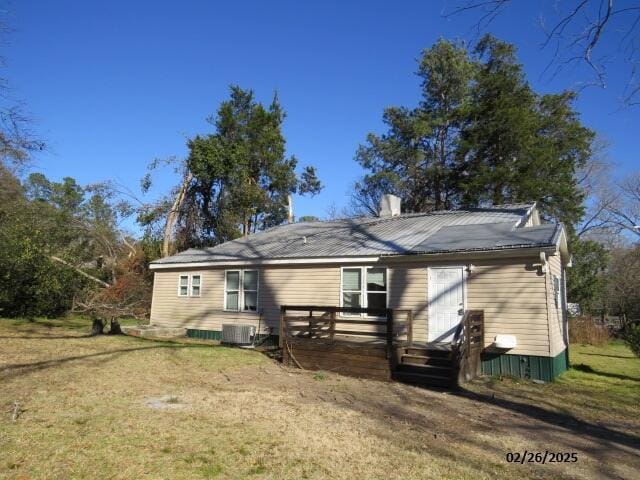 rear view of house with central air condition unit, metal roof, a lawn, and a wooden deck