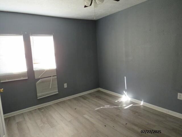 empty room featuring ceiling fan, baseboards, and wood finished floors