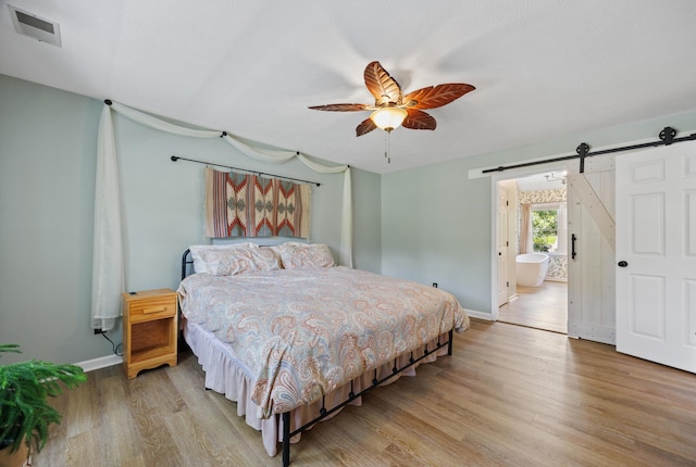 534 Creekridge Rd, Aiken, SC 29803 - bedroom featuring a barn door, light wood-style floors, ceiling fan, and ensuite bath