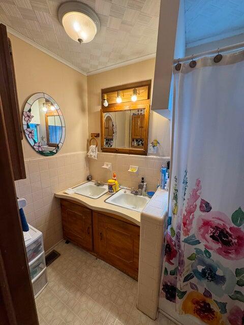 289 Cathy Dr, Warrenville, SC 29851 - bathroom featuring tile walls, ornamental molding, double vanity, a shower with shower curtain, and wainscoting