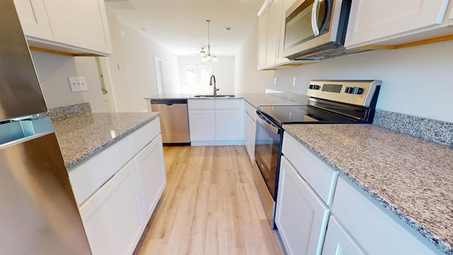 kitchen with white cabinetry, appliances with stainless steel finishes, kitchen peninsula, and light stone counters