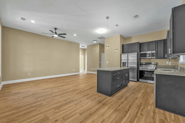 kitchen featuring ceiling fan, sink, decorative light fixtures, a kitchen island, and appliances with stainless steel finishes