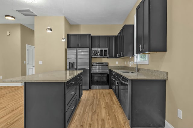 kitchen featuring appliances with stainless steel finishes, decorative light fixtures, light stone counters, and sink