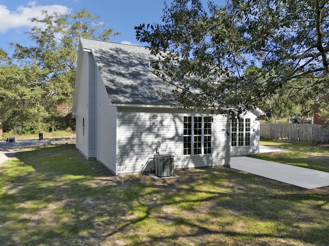 rear view of house featuring a patio area, central air condition unit, and a yard