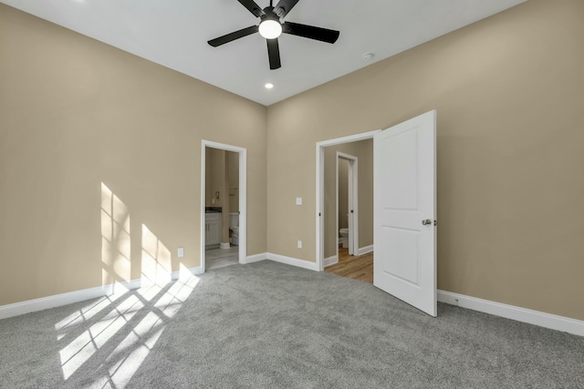 unfurnished bedroom featuring ceiling fan, light colored carpet, and ensuite bath