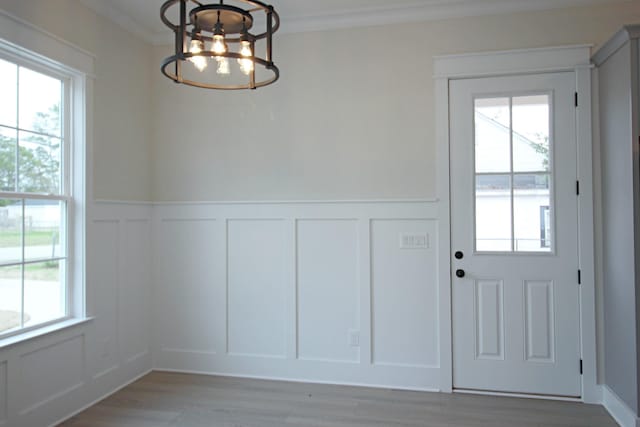 interior space featuring a wealth of natural light, crown molding, a chandelier, and light hardwood / wood-style flooring