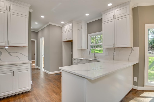 4 Shadowmoor Ct, North Augusta, SC 29841 - kitchen with light stone countertops, white cabinetry, wood finished floors, ornamental molding, and a peninsula