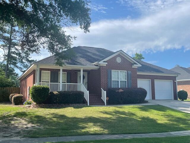 507 Julia Ct, Grovetown, GA 30813 - ranch-style home with a porch, an attached garage, concrete driveway, a front lawn, and brick siding