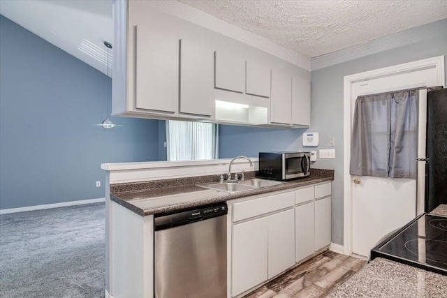 kitchen featuring appliances with stainless steel finishes, a textured ceiling, light colored carpet, sink, and white cabinetry