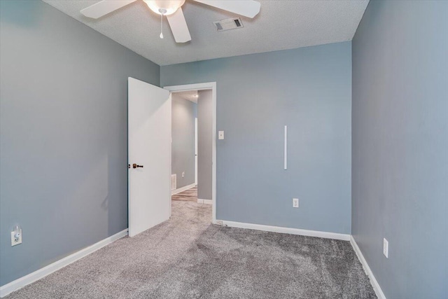 carpeted spare room featuring ceiling fan and a textured ceiling